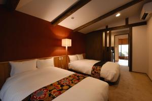 Cette chambre d'hôtel comprend 2 lits avec des draps blancs. dans l'établissement Ubusuna no Sato TOMIMOTO, à Ando