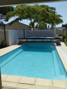 a swimming pool with blue water in a backyard at Studio meublé et équipé avec jardin et terrasse privée in Beurlay