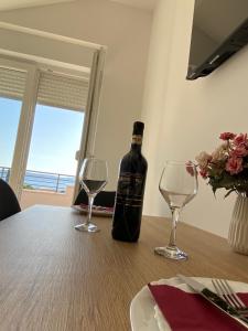 a bottle of wine sitting on a table with two glasses at Theros in Bibinje