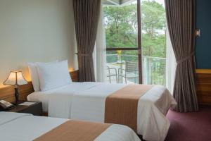 a hotel room with two beds and a balcony at Grand Sierra Pines Baguio in Baguio