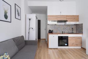 a living room with a gray couch and a kitchen at RentPlanet - Studio Żeromskiego in Wrocław