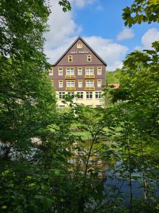 ein großes Gebäude wird durch die Bäume gesehen in der Unterkunft GreenLine Ferienhotel Forelle in Thale