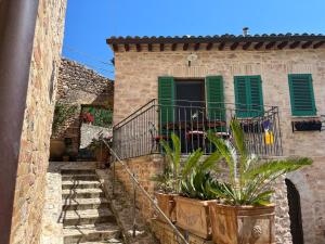 a stone house with green shutters and potted plants at A Room With A View-Spello in Spello