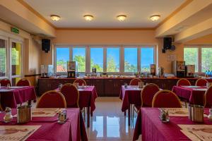 a restaurant with red tables and chairs and windows at Fried Kastély Hotel Simontornya in Simontornya