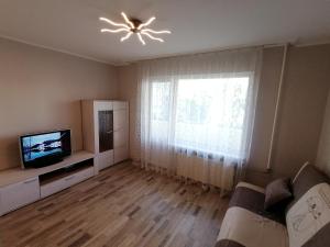 a living room with a couch and a television and a window at Jurmala Kauguri in Jūrmala