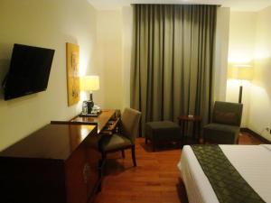 a hotel room with a bed and a desk and a bed and a desk at Manado Quality Hotel in Manado
