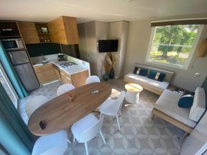 a kitchen and living room with a wooden table and chairs at Logement Clos des Anges in Ménilles