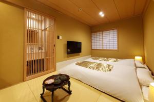 a bedroom with a bed and a tv and a table at Itsukushimahigashimonzen Kikugawa in Miyajima