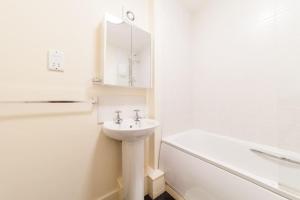 een witte badkamer met een wastafel en een bad bij Fusilier apartment wrexham city in Wrexham