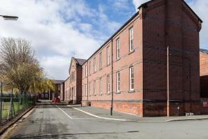 a large red brick building on a street at Fusilier apartment wrexham city in Wrexham