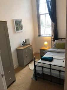 a bedroom with a bed and a dresser and a window at Fusilier apartment wrexham city in Wrexham