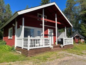 ein kleines rotes Haus mit einer weißen Veranda und einer Veranda in der Unterkunft Vikajärvi Lake View Experience Igloos in Rovaniemi