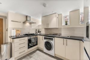 a kitchen with white cabinets and a washer and dryer at Stunning Church Conversion Apartment in Sheffield