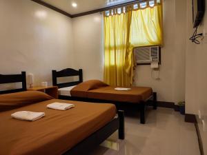 Cette chambre comprend deux lits et une fenêtre avec des rideaux jaunes. dans l'établissement El Juliana Hotel, à Vigan