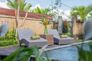 2 sedie e un tavolo accanto alla piscina di NILUH Private Villas ad Ubud