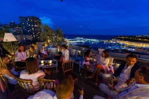 um grupo de pessoas sentadas numa varanda à noite em Penthouse Roof 6 pieces à Monaco em Monte Carlo