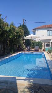 a swimming pool with an umbrella next to a house at Αρχοντικό Ταξίμι (Μουντζουρίδη) in Argalasti