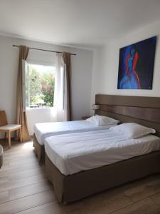 a bedroom with two beds and a window at Hôtel & Restaurant Les Mouettes in Belgodère