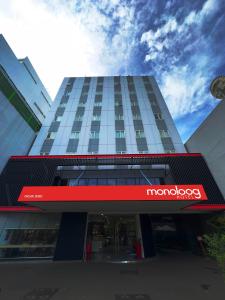 a tall building with a sign in front of it at Monoloog Hotel Surabaya in Surabaya