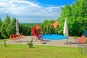 eine Gruppe von Stühlen und ein Pool mit Sonnenschirmen in der Unterkunft Fried Kastély Hotel Simontornya in Simontornya