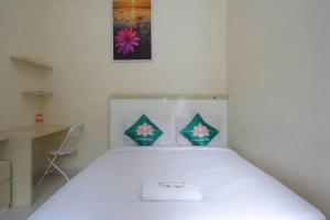een slaapkamer met een wit bed met 2 kussens bij Teratai Guesthouse Mitra RedDoorz near Tugu Yogyakarta in Kejayan