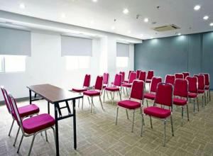 a conference room with red chairs and a table at Monoloog Hotel Palembang in Palembang