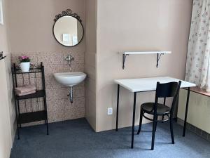 a bathroom with a sink and a table and a chair at Penzion Hají in Janov nad Nisou