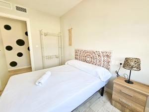 a bedroom with a white bed and a lamp at Buenavista Frente al mar - Alojamientos La Torre in Torre del Mar