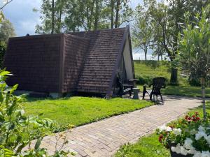 una pequeña casa con un techo inclinado en un jardín en Hotelhuisjes Oosterleek, en Oosterleek