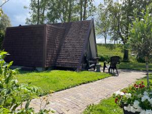 a small house with a pitched roof in a garden at Hotelhuisjes Oosterleek in Oosterleek