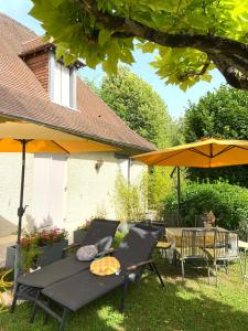 eine Terrasse mit einem Tisch, Stühlen und Sonnenschirmen in der Unterkunft Jolie Perigourdine 7 Couchages in Champcevinel