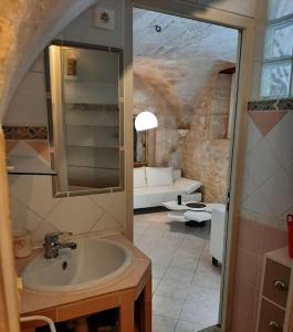 ein Badezimmer mit einem Waschbecken und ein Wohnzimmer in der Unterkunft Appartement cosy au cœur d'Uzès in Uzès