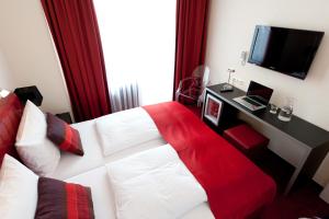 um quarto de hotel com uma cama branca com um cobertor vermelho em Hotel Esplanade em Colónia