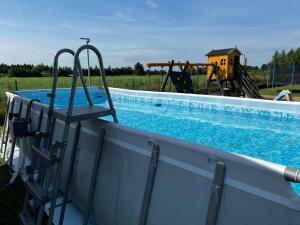a pool with two chairs next to a playground at Domki Masztowa Przystań in Gąski