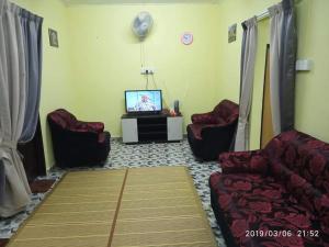 ein Wohnzimmer mit 2 Stühlen und einem TV in der Unterkunft La' Homestay in Kota Bharu