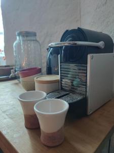 een aanrecht met een koffiezetapparaat en vier kopjes erop bij Magnanerie du Perrier : studio indépendant au pied des Cévennes in Pompignan