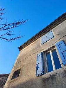 een gebouw met blauwe luiken en een raam erop bij Magnanerie du Perrier : studio indépendant au pied des Cévennes in Pompignan