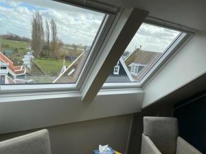 two skylight windows in a room with chairs at Bed and Breakfast De Pepersteeg in Marken