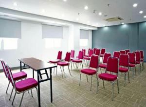 a conference room with red chairs and a table at Monoloog Hotel Makassar in Makassar