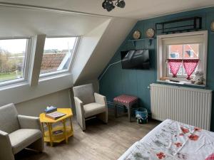 a small room with a bed and a table and chairs at Bed and Breakfast De Pepersteeg in Marken