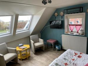 een kleine kamer met een bed en een tafel en stoelen bij Bed and Breakfast De Pepersteeg in Marken