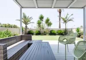 a patio with a wooden bench and chairs at Yama SEA VIEW 4BR in Nahariyya