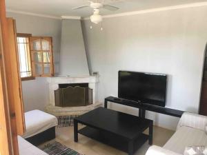 a living room with a tv and a couch and a table at Karipidis houses in Nea Iraklia