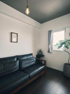 un sofá de cuero negro en una sala de estar con ventana en intro vetta 1003 Free parking en Kumamoto