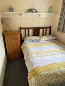 a bedroom with a bed and a wooden dresser at Bryn Goleu, Mersey Street, Borth-y-Gest in Porthmadog