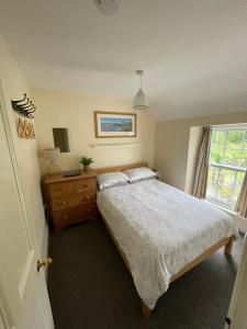 een slaapkamer met een bed, een dressoir en een raam bij Bryn Goleu, Mersey Street, Borth-y-Gest in Porthmadog
