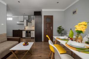 a living room and kitchen with a table and yellow chairs at Market Square Corner Apartment Kuźnicza by Renters in Wrocław