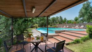 eine Terrasse mit einem Tisch und Stühlen sowie einem Pool in der Unterkunft VILLA IRENE 6, Emma Villas in Montecarlo