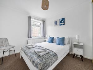 een slaapkamer met een bed met blauwe kussens en een raam bij Pass the Keys Modern Spacious 3BR Bungalow Parking Oxford in Oxford