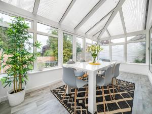 a dining room with a white table and chairs and windows at Pass the Keys Modern Spacious 3BR Bungalow Parking Oxford in Oxford